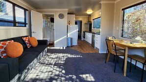 Un espacio habitable compacto con sofá, mesa de comedor y kitchenette.