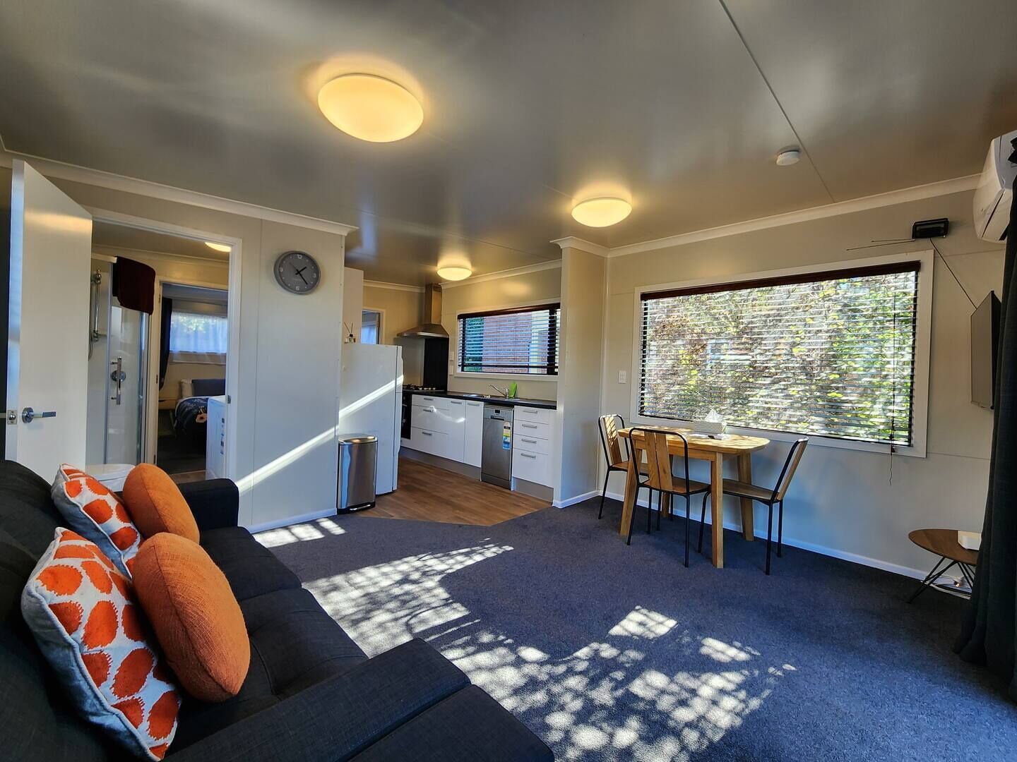 A compact living space with a kitchenette, a dining area, and a sofa with patterned cushions.