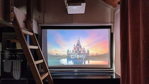 Ein Flachbildfernseher an der Wand, der eine Szene aus einem Schloss zeigt, mit dem Disney-Logo.