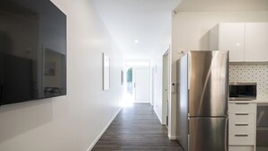 Une cuisine moderne dotée d’un réfrigérateur en acier inoxydable, de meubles blancs et d’un dosseret carrelé.