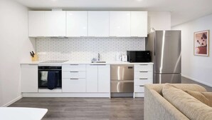 A modern kitchen with white cabinets, a stainless steel refrigerator, and a microwave. - Modern Central Apartment, Flexible Bed Options (Dunedin)