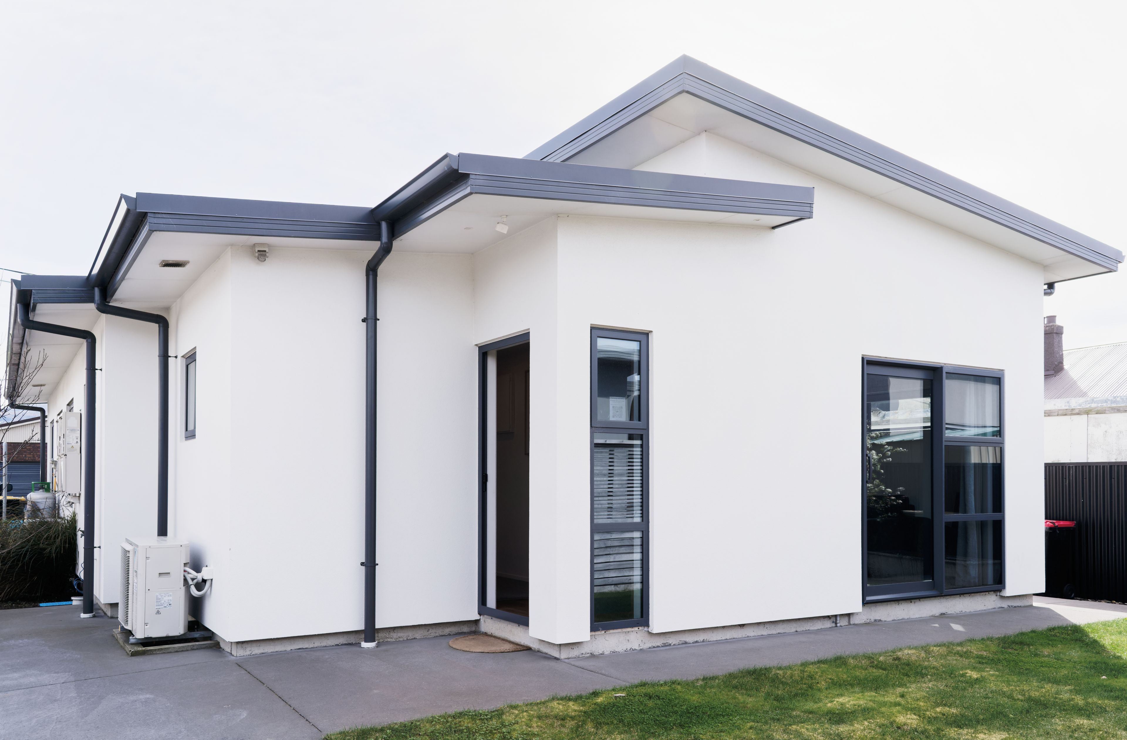 A modern two-story house with a flat roof, large windows, and a visible garage door.