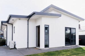 Una moderna casa a due piani con tetto piatto, ampie finestre e un garage ben visibile.