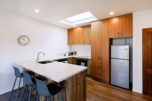 Una cucina moderna con isola centrale, mobili in legno, frigorifero in acciaio inossidabile e forno integrato.
