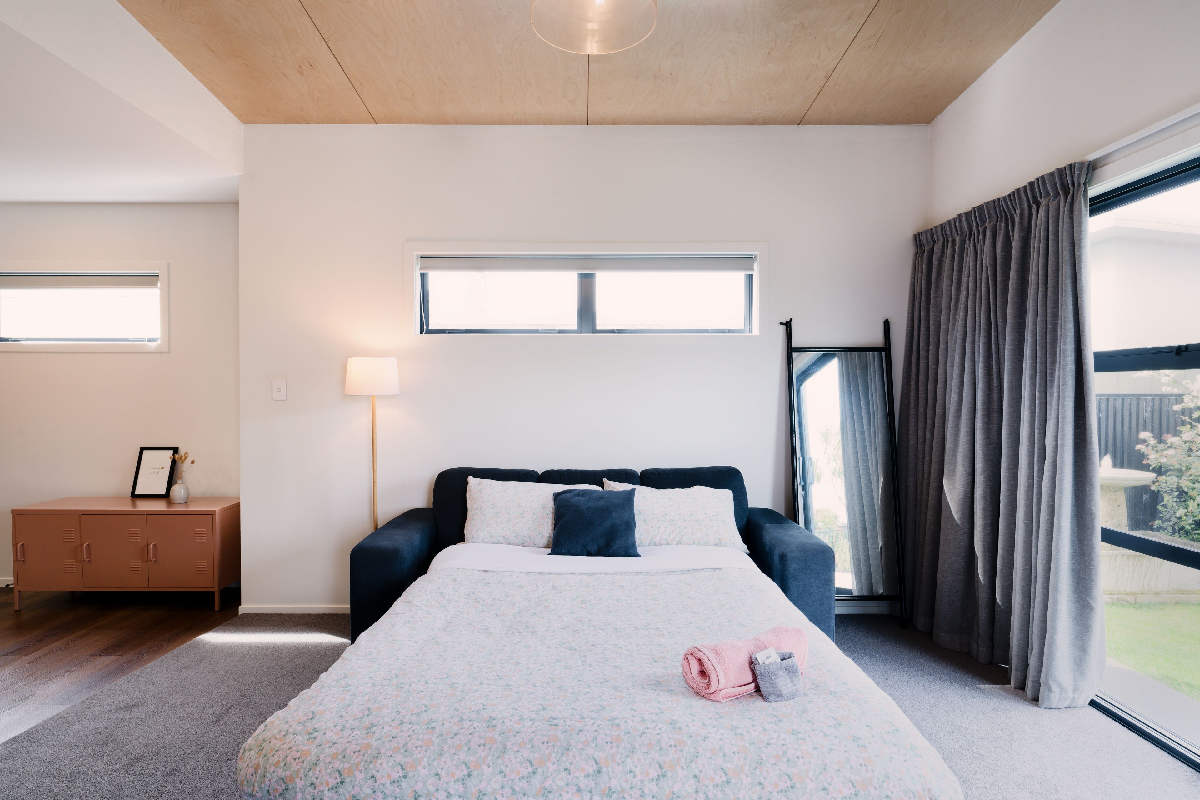 Quarto com cama, mesa de cabeceira, luminária, janela e vista para o exterior.