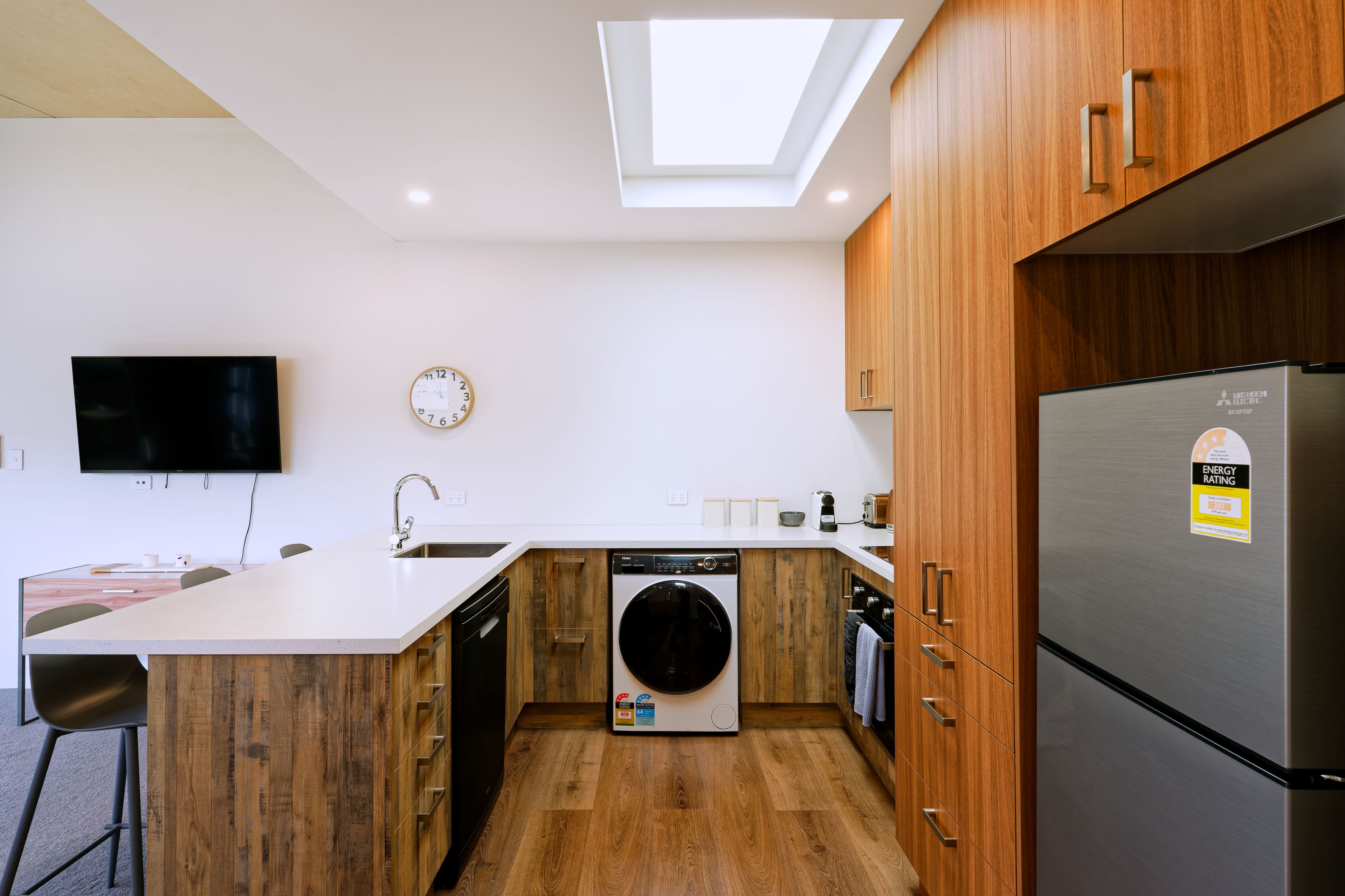 A modern kitchen with a built-in dishwasher, a washing machine, and a refrigerator.