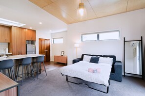 A modern bedroom with a bed, bedside table, and a window.
