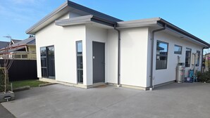 A modern single-story house with a garage, large windows, and a clean, well-maintained exterior. - Sleek Suite by the Sand (2-bedroom) (Dunedin)