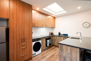 Eine moderne Küche mit Holzschränken, einer integrierten Waschmaschine und einer großen Kücheninsel mit Spüle.