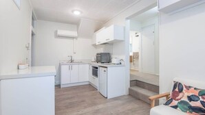 A compact kitchen with white cabinets, a microwave, and a sink. - Roslyn Retreat: Garden 2-Bed Suite + Kitchenette (Dunedin)