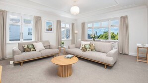 A spacious living room with two sofas, a coffee table, and large windows with curtains.