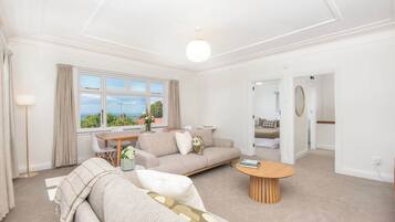 A spacious living room with a large window, a sofa, a coffee table, and a dining area.