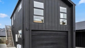 A modern two-story building with a dark exterior, large windows, and a garage door.