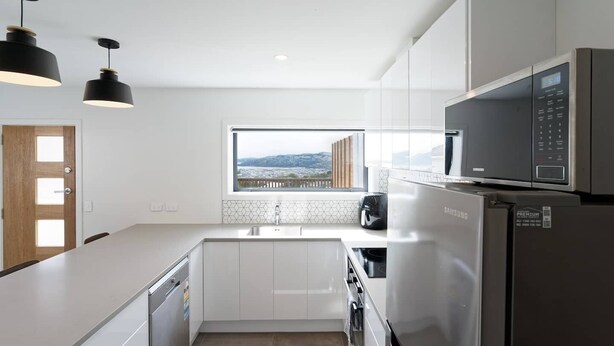 Una cucina moderna con mobili bianchi, elettrodomestici in acciaio inossidabile, una finestra con vista e luci a sospensione.