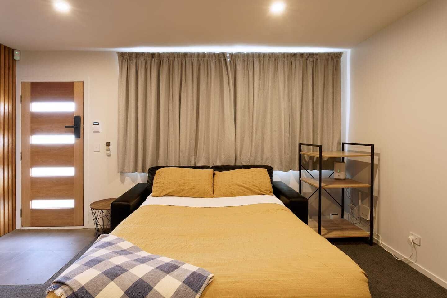 Ein Schlafzimmer mit Bett, Nachttisch, Stuhl, Kleiderschrank und einem Fenster mit Vorhängen.