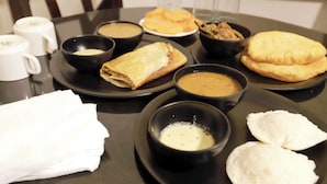 A table set with various dishes, including bowls of soup and plates of flatbreads. - Hotel Triton Grand (New Delhi)