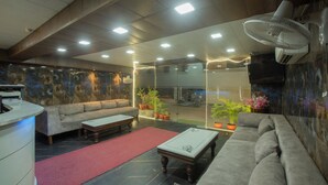 A modern lobby with a sofa, a coffee table, and a reception desk. - Hotel Triton Grand (New Delhi)