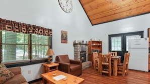 A cozy living room with a fireplace, wooden furniture, and a stone fireplace surround.