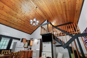 Een moderne keuken met houten plafond en een trap naar een hoger niveau.
