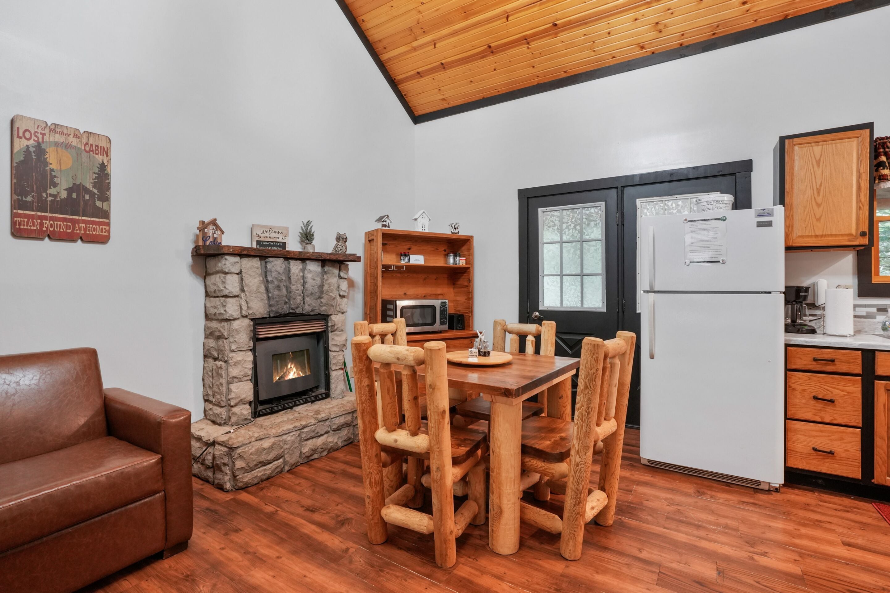 Ein gemütliches Blockhaus-Interieur mit Kamin aus Naturstein, Holztisch und Küchenzeile.