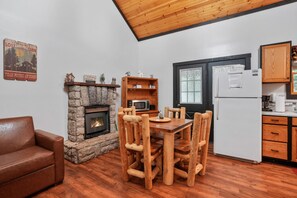 Een gezellig houten interieur met een stenen openhaard, een houten eettafel en een kitchenette.