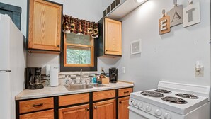 A kitchen with wooden cabinets, a white stove, and a window with a plaid curtain.