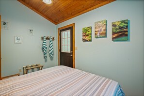 Une chambre à coucher avec un lit, une tête de lit en bois, une porte et des œuvres d’art accrochées au mur.