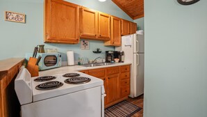 Una cocina con armarios de madera, estufa blanca, tostadora y refrigerador.
