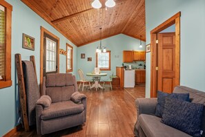 Ein gemütliches Interieur mit Holzbalkendecke, einer Essecke mit Tisch und Stühlen sowie einer Küche im Hintergrund.