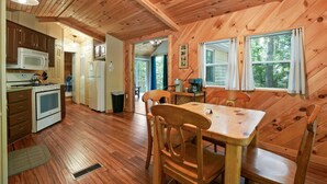 A wooden cabin interior with a kitchen, dining area, and a view of the outdoors. - Hidden Ridge Cabin | Big Pine Retreat, Trails (Rockbridge)
