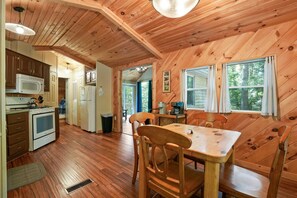 A wooden cabin interior with a kitchen, dining area, and a view of the outdoors. - Hidden Ridge Cabin | Big Pine Retreat, Trails (Rockbridge)