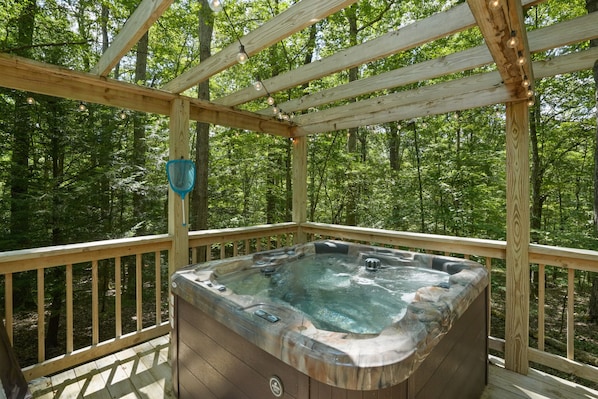 A hot tub on a wooden deck surrounded by a forest.
