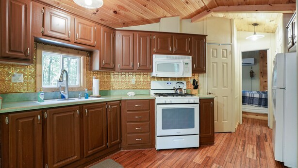 A kitchen with wooden cabinets, a white stove, and a microwave. - Hidden Ridge Cabin | Big Pine Retreat, Trails (Rockbridge)