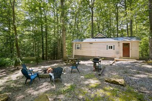 A cabin with a fire pit, outdoor seating, and a grill in a wooded area. - Hidden Ridge Cabin | Big Pine Retreat, Trails (Rockbridge)