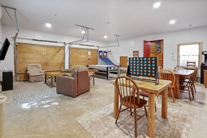 A spacious room with a wooden table and chairs, a sofa, a play area with a slide, and a basketball hoop. - Hummingbird Lodge at Big Pine Retreat, Indoor Pool (Rockbridge)