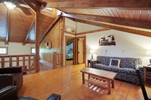 Ein Holzinnenraum mit einer Couch, einem Tisch und einer Treppe.