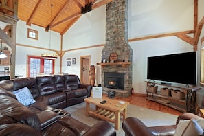 A cozy living room with a stone fireplace, leather sofas, and a television. - Hummingbird Lodge at Big Pine Retreat, Indoor Pool (Rockbridge)