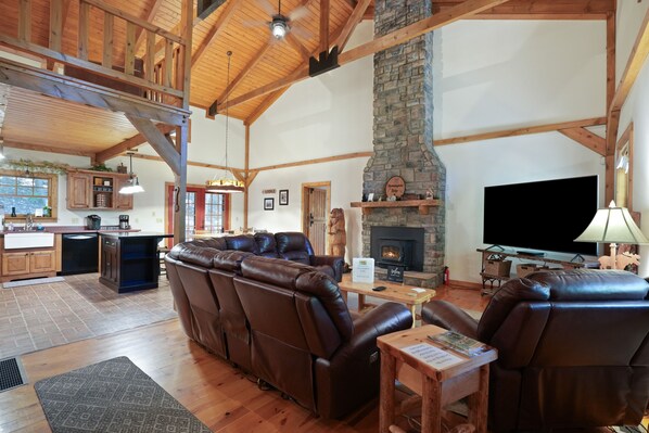 A spacious living room with leather sofas, a stone fireplace, and a television. - Hummingbird Lodge at Big Pine Retreat, Indoor Pool (Rockbridge)