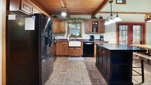 A kitchen with wooden cabinets, a black refrigerator, and a wooden dining table.