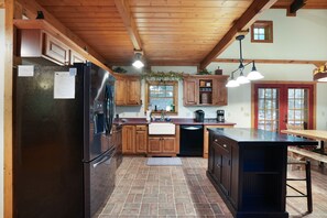 A kitchen with wooden cabinets, a black refrigerator, and a wooden dining table. - Hummingbird Lodge at Big Pine Retreat, Indoor Pool (Rockbridge)