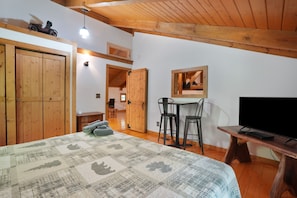 Un dormitorio con cama, armario de madera, escritorio, sillas y televisor.