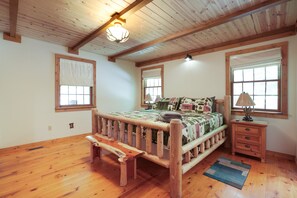 A bedroom with a wooden bed, a bench, a nightstand, and a window. - Hummingbird Lodge at Big Pine Retreat, Indoor Pool (Rockbridge)