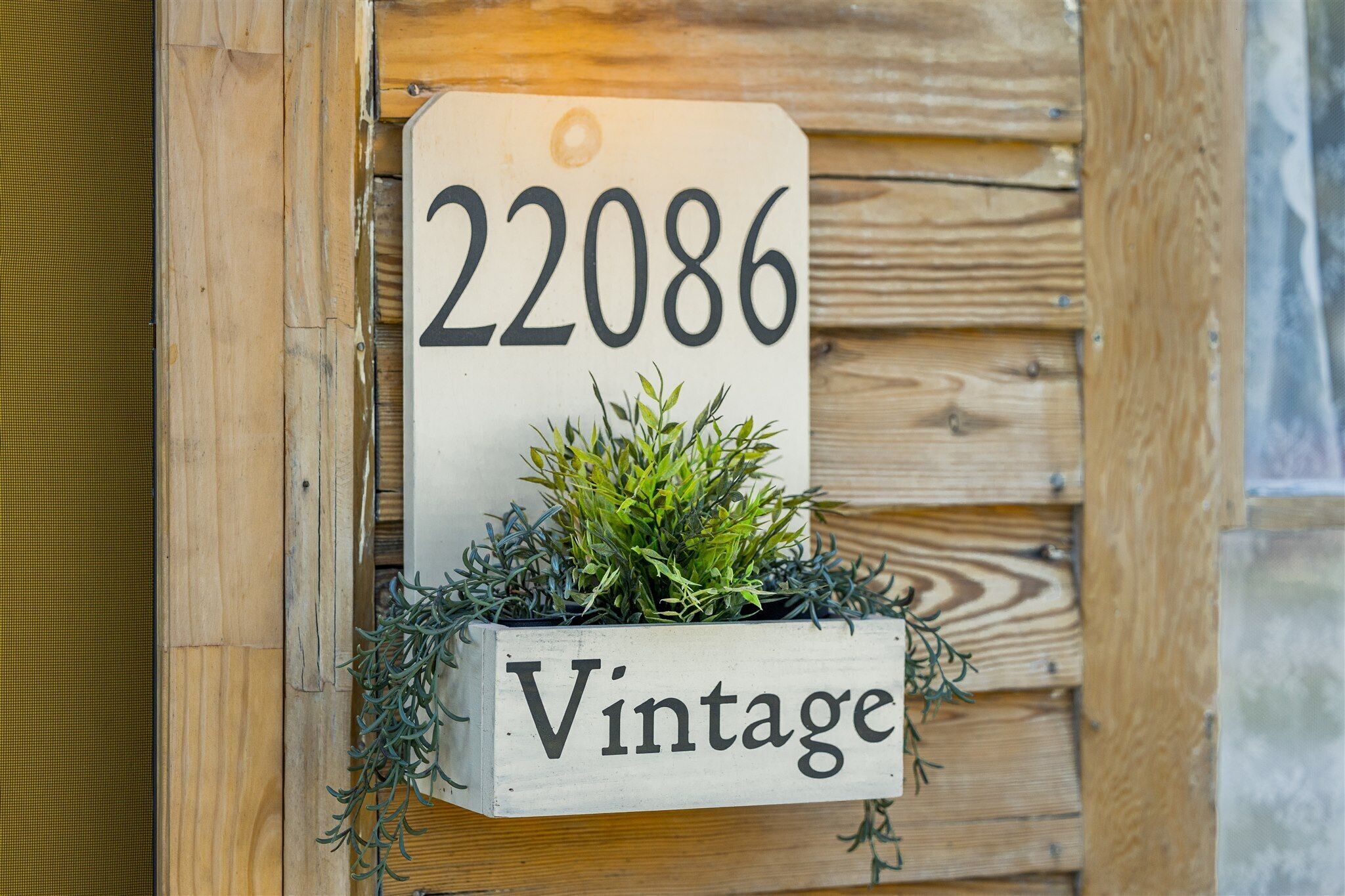 A wooden sign with the number 22086 and the word "Vintage" on it, mounted on a wooden wall.