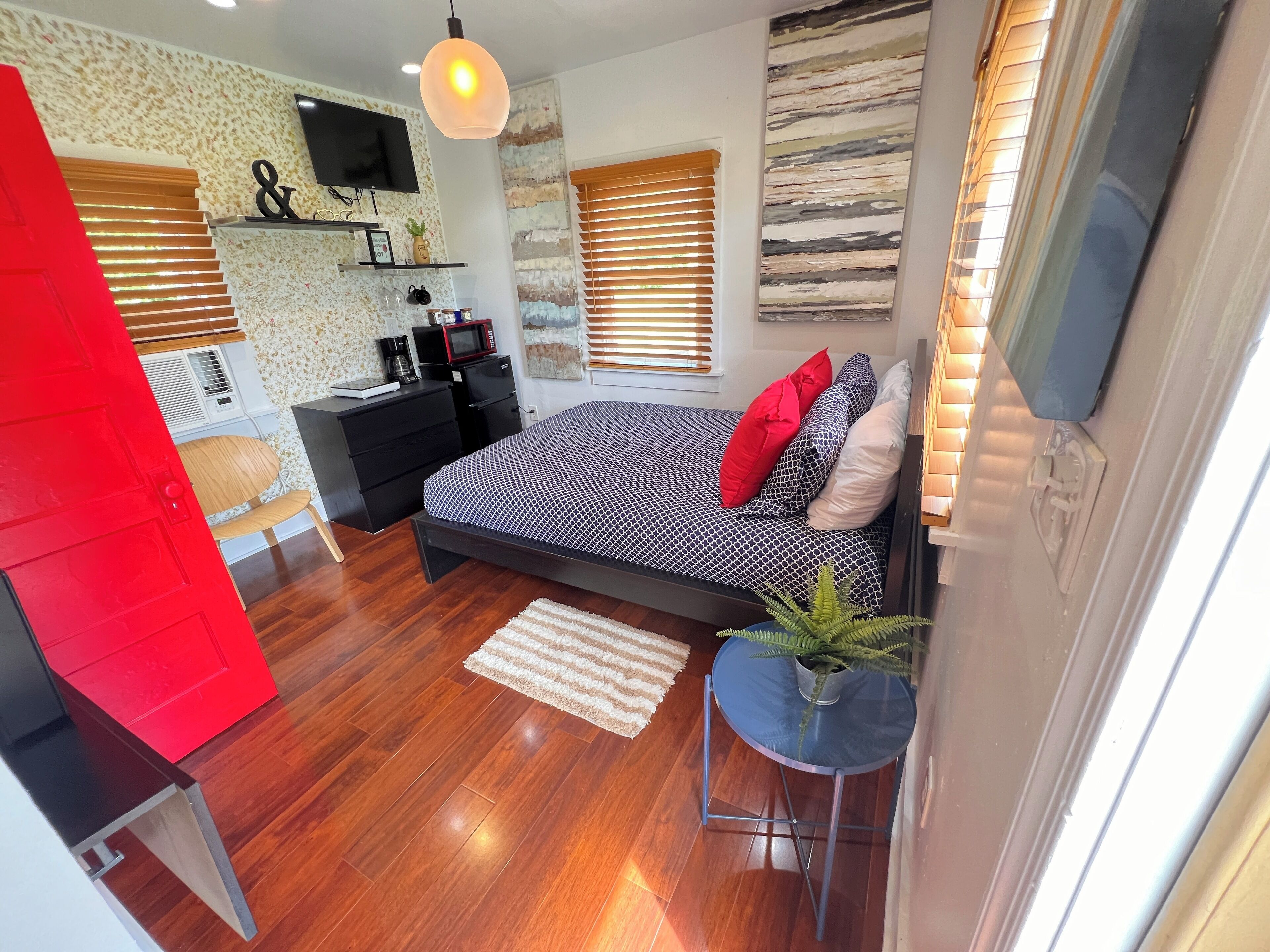 A modern bedroom with a bed, bedside table, and a red door.