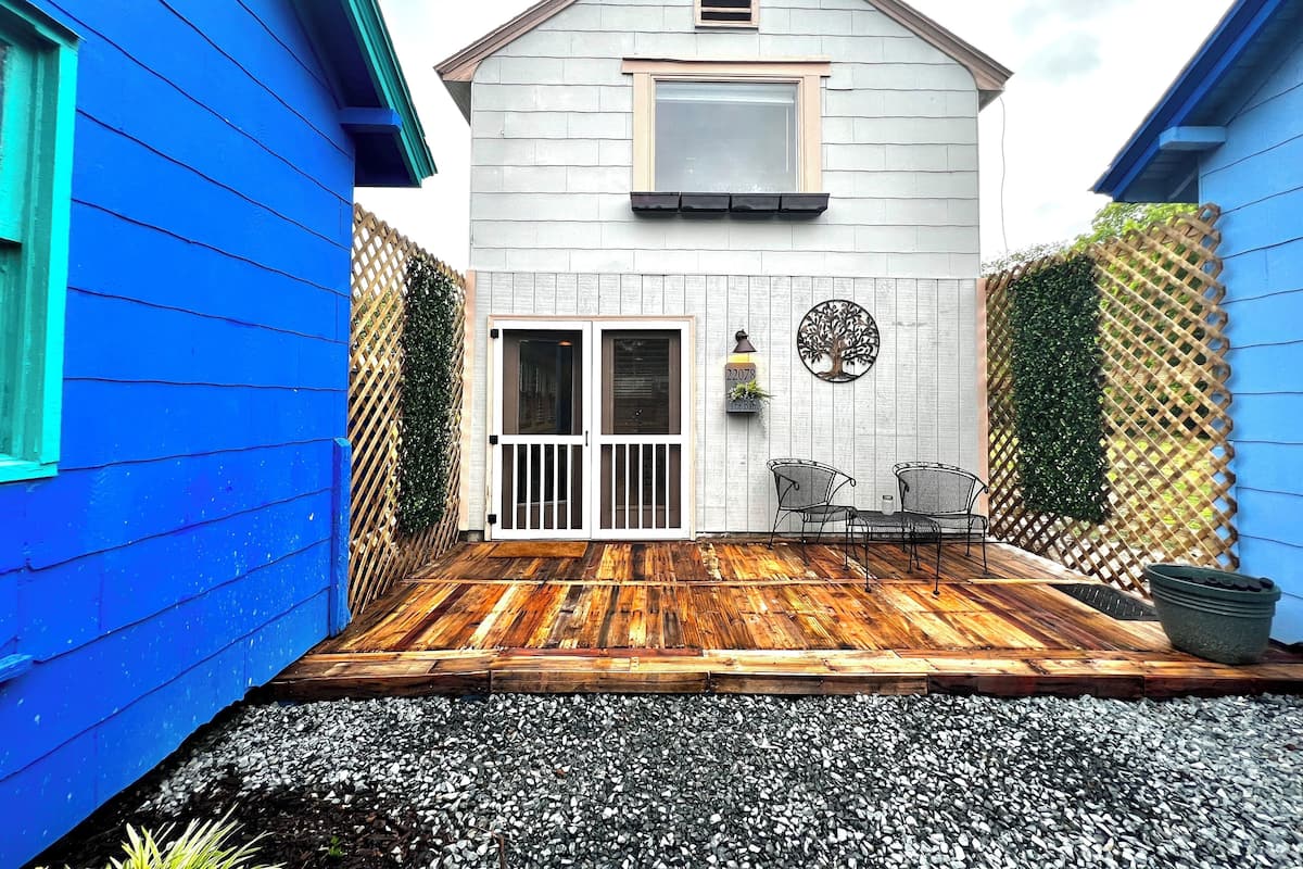 Une maison avec une terrasse en bois, un petit espace patio et une boîte aux lettres.