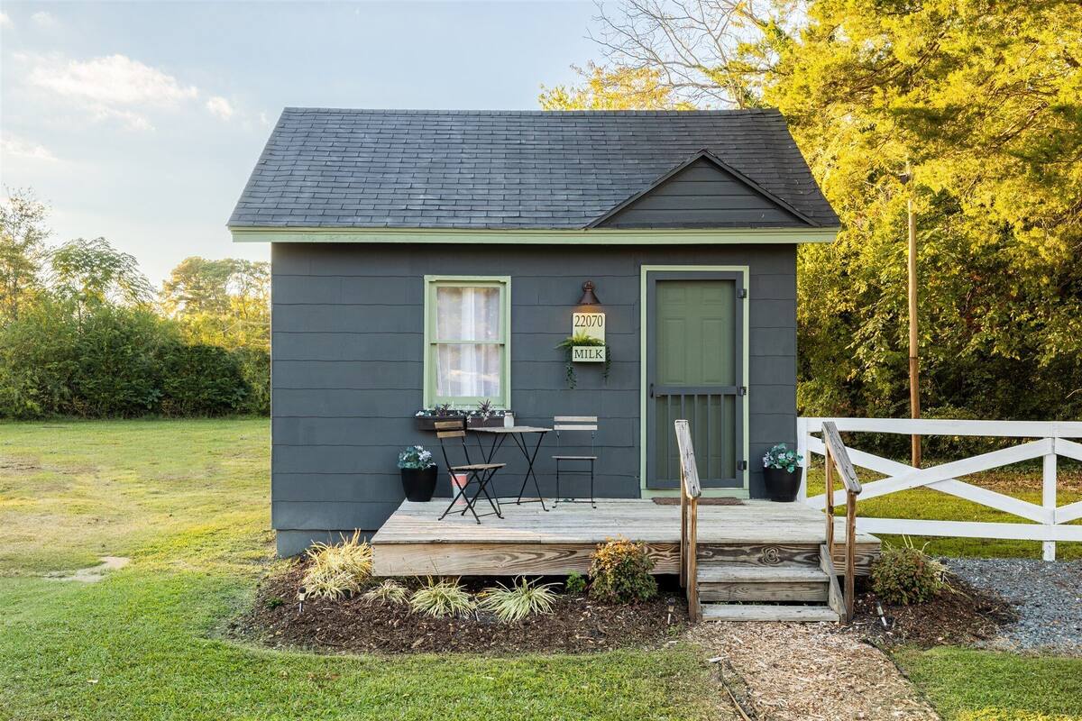 Une petite maison à l’extérieur sombre, avec une porte verte et une boîte aux lettres portant l’inscription « 22070 LAIT ».
