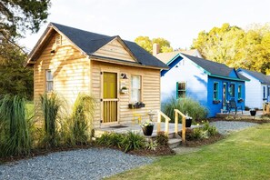 A row of cabins with a gravel driveway, wooden steps, and potted plants. - Cape Charles Tiny Livin (Cape Charles)