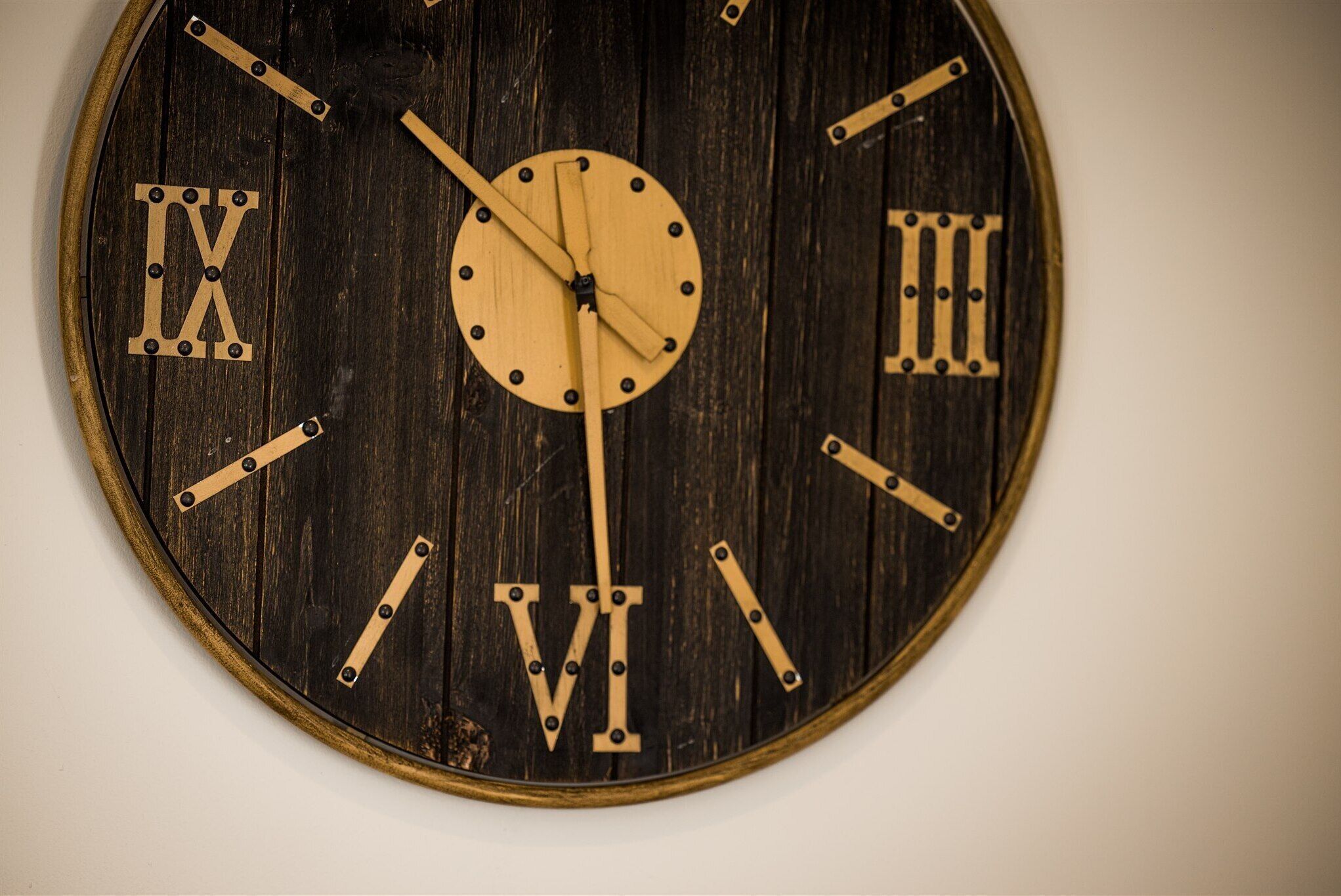 A wooden wall clock with Roman numerals and a minimalist design.