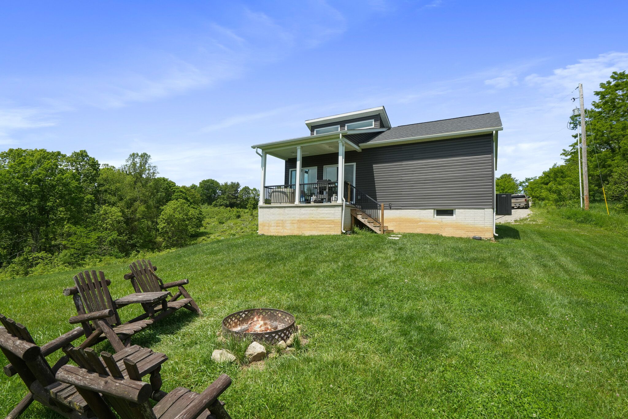 A modern house with a covered porch, a fire pit, and outdoor seating.