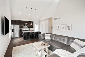 A modern living room with a leather sofa, a coffee table, and a TV mounted on the wall.